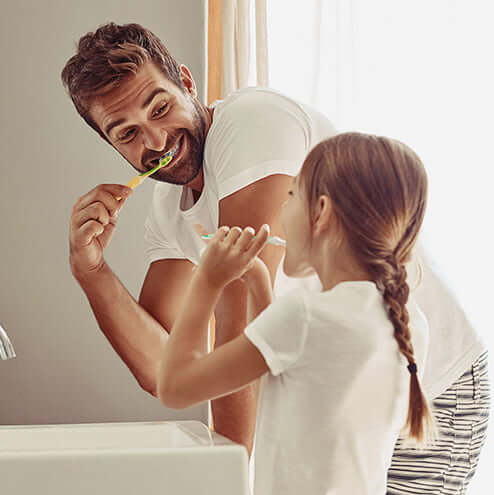 father and daughter brushing their teeth together