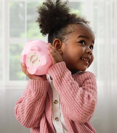little girl holding a piggy bank