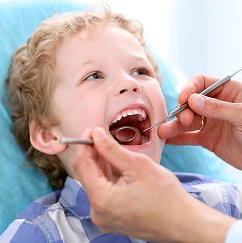 young boy having his teeth examined by a dentist