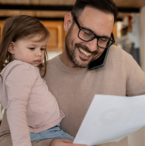 dad on the phone and holding toddler